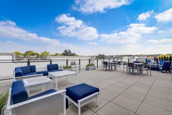 A patio with blue cushions and white furniture overlooks a cityscape.